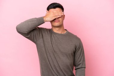Beyaz tenli yakışıklı adam pembe arka planda izole edilmiş gözlerini elleriyle kapatıyor. Bir şey görmek istemiyorum.