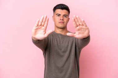 Pembe arka planda izole edilmiş beyaz, yakışıklı genç adam dur hareketi yapıyor ve hayal kırıklığına uğruyor.