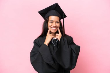 Young university Colombian woman graduate isolated on pink background smiling with a happy and pleasant expression