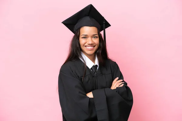 Young university Colombian woman graduate isolated on pink background with arms crossed and looking forward