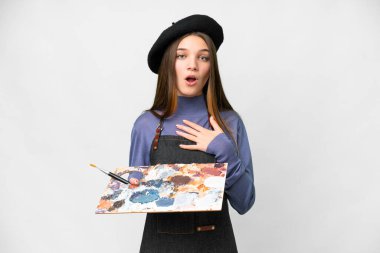 Young artist man holding a palette over isolated white background surprised and shocked while looking right