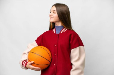 Teenager girl playing basketball over isolated white background looking side