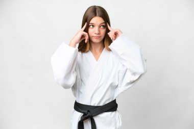 Teenager girl doing karate over isolated white background having doubts and thinking