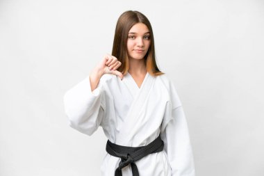 Teenager girl doing karate over isolated white background showing thumb down with negative expression