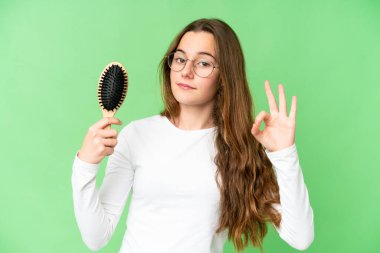 Teenager girl with hair comb over isolated chroma key background showing ok sign with fingers