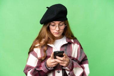 Teenager girl over isolated chroma key background using mobile phone