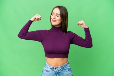 Young beautiful woman over isolated chroma key background doing strong gesture