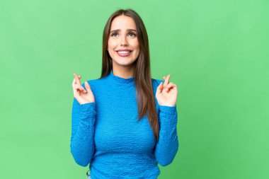 Young beautiful woman over isolated chroma key background with fingers crossing and wishing the best