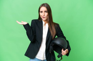Young Asian woman with a motorcycle helmet over isolated chroma key background having doubts while raising hands