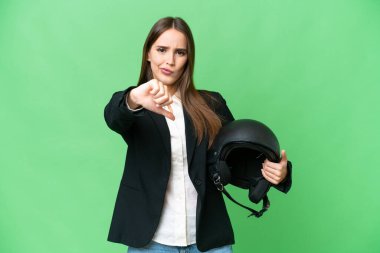 Young Asian woman with a motorcycle helmet over isolated chroma key background showing thumb down with negative expression