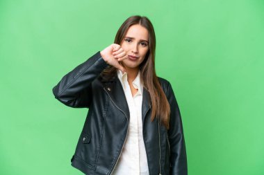 Young beautiful woman over isolated chroma key background showing thumb down with negative expression