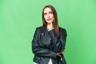 Young beautiful woman over isolated chroma key background having doubts while looking up
