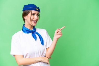 İzole edilmiş kroma anahtar arka plan üzerinde uçak hostesi parmak göstererek bir ürün sunar