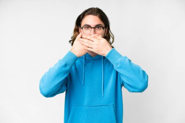 İzole edilmiş beyaz arka planı olan genç yakışıklı adam elleriyle ağzını kapatıyor.