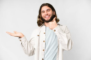 İzole edilmiş beyaz arka plan üzerinde genç yakışıklı bir adam. Avucunun içinde hayali bir şey tutuyor. Bir ilan vermek için.