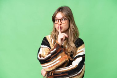 İzole edilmiş krom anahtar geçmişi olan genç bir kız parmağını ağzına koyan sessiz bir jest işareti gösteriyor.