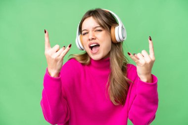 Genç kız izole edilmiş krom anahtar arka planda müzik dinliyor rock hareketler yapıyor