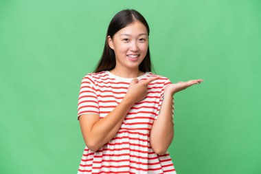 Asyalı genç bir kadın izole edilmiş olarak cep telefonuyla mesaj gönderiyor.