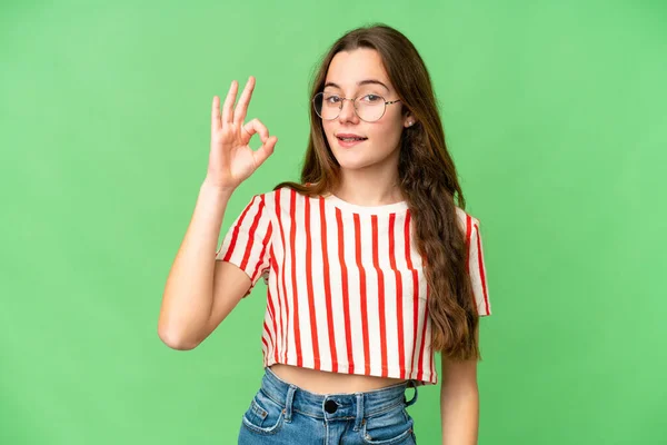 Teenager girl over isolated chroma key background showing ok sign with fingers