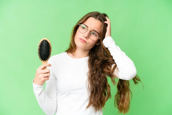 Teenager girl with hair comb over isolated chroma key background having doubts and with confuse face expression