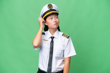 Uçak pilotu Asyalı kadın izole edilmiş arka planda kuşkuları ve kafa karıştırıcı yüz ifadesi var.