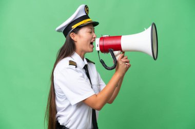 Airplane pilot Asian woman over isolated background shouting through a megaphone