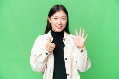 Genç Asyalı kadın izole edilmiş krom anahtar altmış parmaklı sayıyor.