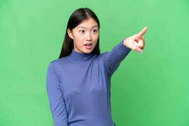 Genç Asyalı kadın izole edilmiş krom anahtar geçmişi gösteriyor.