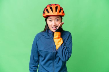 İzole edilmiş krom anahtar geçmişi olan genç bisikletçi kadın. Şaşırmış ve şok olmuş yüz ifadesi var.
