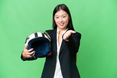 Motosiklet kasklı genç Asyalı kadın izole edilmiş bir krom anahtar geçmişi var. İyi bir anlaşma için el sıkışıyor.