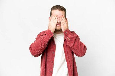 Genç, sarışın, soyutlanmış, beyaz arka planda, gözleri elleriyle kaplayan adam.