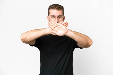 Soyutlanmış beyaz arka planda genç, sarışın bir adam bir hareketi durdurmak için eliyle jest yapıyor.