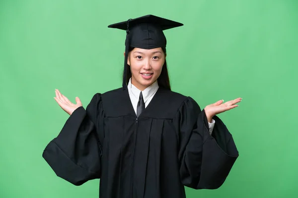 Young university graduate Asian woman over isolated background with shocked facial expression