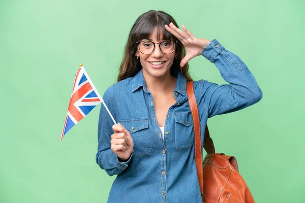 Young caucasian woman holding an United Kingdom flag over isolated background with surprise expression