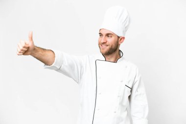 Sarışın genç adam Şef izole edilmiş beyaz arka planda baş parmak hareketi yapıyor.