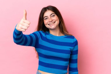 Pembe arka planda izole edilmiş beyaz bir kadın. Başparmakları havada. Çünkü iyi bir şey oldu.