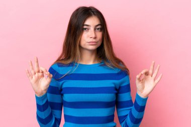 Zen pozunda pembe arka planda izole edilmiş beyaz bir kadın.