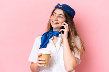 Airplane stewardess caucasian woman isolated on pink background holding coffee to take away and a mobile