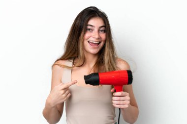Young caucasian woman holding a hairdryer isolated on white background with surprise facial expression