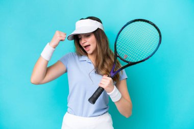 Genç tenisçi kadın mavi arka planda tek başına zaferi kutluyor.