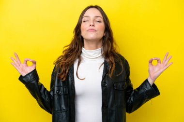 Zen pozisyonunda sarı arka planda izole genç beyaz kadın.