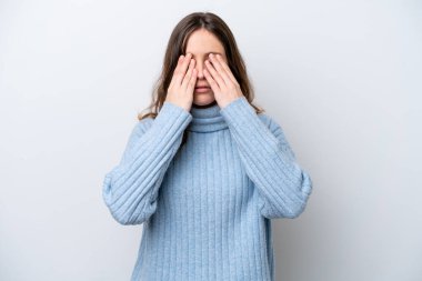 Beyaz arka planda izole edilmiş beyaz tenli genç bir kadın gözlerini elleriyle kapatıyor.