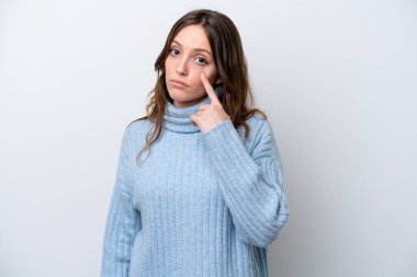 Beyaz arka planda izole edilmiş genç beyaz kadın bir şey gösteriyor.