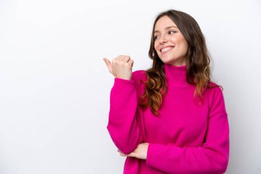 Beyaz arka planda izole edilmiş genç beyaz kadın bir ürünü sunmak için kenarı işaret ediyor.