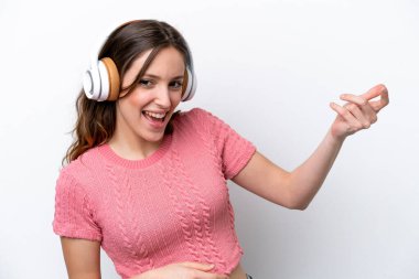 Beyaz arka planda izole edilmiş beyaz bir kadın müzik dinliyor ve gitar hareketi yapıyor.
