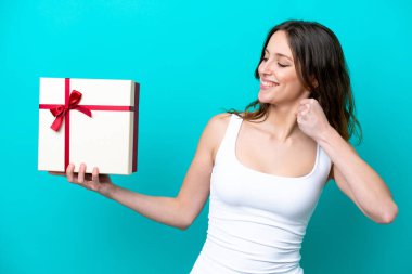 Mavi arka planda zafer kutlamaları yapan Kafkasyalı genç bir kadın elinde bir hediye tutuyor.