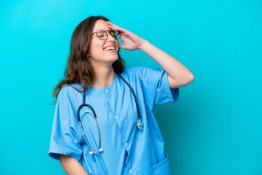 Genç cerrah kadın. Mavi arka planda izole edilmiş. Çok gülümsüyor.