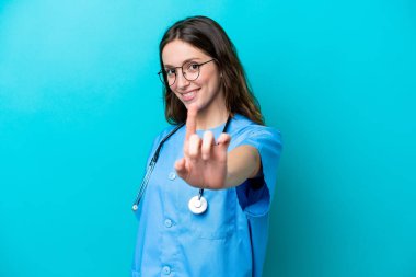 Mavi arka planda izole edilmiş genç cerrah kadın parmağını kaldırıyor ve gösteriyor.
