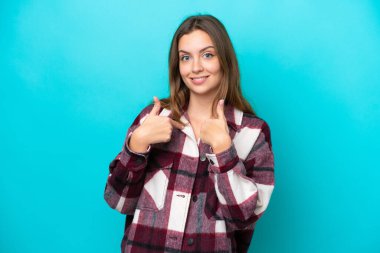 Mavi arka planda yalıtılmış beyaz bir kadın. Şaşırtıcı bir yüz ifadesi var.