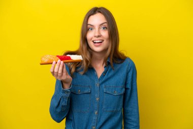 Sarı arka planda elinde saşimi tutan beyaz bir kadın. Şaşırmış ve şok olmuş bir yüz ifadesi var.